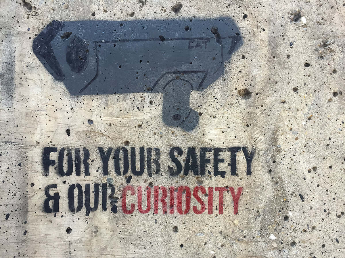 surveillance camera graffiti on a wall